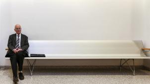 <p>Der Aachener Dompropst Manfred von Holtum vor seiner Zeugenaussage auf einer Bank vor dem Gerichtsssaal.</p>