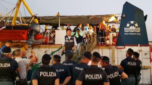 <p>Migranten gehen von Bord des Rettungsschiffs „Sea-Watch 3“ im Hafen der Insel Lampedusa. Das Schiff der deutschen Hilfsorganisation Sea-Watch ist nach dem unerlaubten Anlegen im Hafen der italienischen Insel Lampedusa und der Festnahme der Kapitänin beschlagnahmt worden. Das bestätigte ein Sea-Watch-Sprecher.</p>