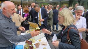 <p>Imker Georges Jost aus Mürringen präsentiert einem Gast aus Bayern seinen Honig.</p>