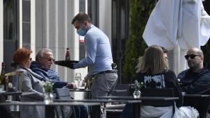 <p>Bedienung mit Maske in einem Straßencafé.</p>
