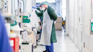 <p>Krankenpfleger bekleiden sich mit Schutzkleidung vor einem Krankenzimmer auf der Intensivstation.</p>