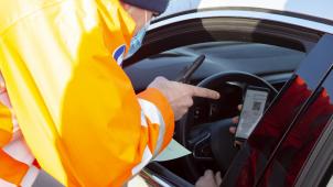 <p>Ein Polizist kontrolliert einen Reiserückkehrer, ob er das PLF-Formular ausgefüllt hat.</p>