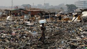 <p>Eine Frau steht auf der Freifläche hinter dem Schrottplatz von Agbogbloshie.</p>
