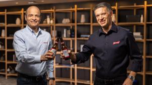 <p>Michel Doukeris (rechts) hat am 1. Juli 2021 die Führung des mit Abstand größten Bierkonzerns weltweit übernehmen. Zuvor hatte Carlo Brito (links) die Geschicke geleitet.</p>