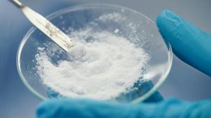 <p>Eine Mitarbeiterin hält in einem Labor eine Glasschale mit Lithiumchlorid in den Händen.</p>