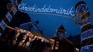 <p>Das Wort „Christkindelsmärik“ prangt in großen beleuchteten Buchstaben an einem Zugang zum Weihnachtsmarkt in Straßburg.</p>