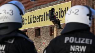 <p>Ein Demonstrant sitzt bei der Räumung des Dorfes Lützerath auf einer Holzkonstruktion vor einem Plakat mit dem Slogan „Lützerath bleibt!“.</p>