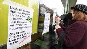 <p>Eine Aktivistin einer Umweltinitiative protestiert in dem sie Plakate an die Scheibe der Grünen Parteizentrale in Nordrhein-Westfalen klebt. Die Aktivisten wollen die Partei daran erinnern, wo ihre Wurzeln sind und sind gegen eine Räumung des Ortes Lützerath durch RWE im</p>
