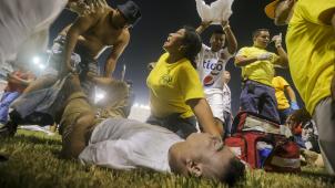 <p>Rettungskräfte kümmern sich um einen verletzten Fan, der auf dem Spielfeld des Cuscatlan-Stadions liegt.</p>