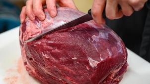 <p>Ein großes Stück Rindfleisch wird mit einem Messer pariert.</p>