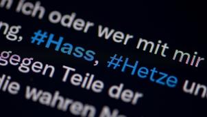 <p>Auf dem Bildschirm eines Smartphones sieht man die Hashtags Hass und Hetze in einem Twitter-Post.</p>