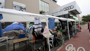 <p>Auch am Freitag nahm die Belegschaft von Auto Brüssel die Arbeit nicht wieder auf. Stattdessen „campen“ Mitarbeiter vor dem Werkseingang.</p>