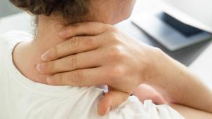 <p>Eine Frau sitzt am Schreibtisch und hält sich die Hand an den Nacken: Bessere Lebensqualität trotz Long Covid.</p>