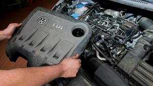 <p>Ein KFZ-Servicetechniker hält die Abdeckung vor einem vom Abgas-Skandal betroffenen 2.0l TDI Dieselmotor vom Typ EA189 in einem VW Touran in einer Autowerkstatt.</p>