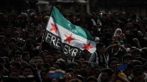 <p>Menschen schwenken eine Fahne der syrischen Opposition während einer Massendemonstration zum zehnten Jahrestag des Beginns des syrischen Bürgerkriegs.</p>