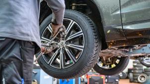 <p>Ein Winterreifen wird in einer Werkstatt an ein Auto montiert.</p>