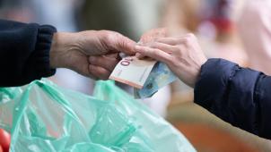 <p>Eine Frau bezahlt mit Bargeld auf einem Wochenmarkt ihre Einkäufe.</p>