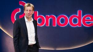 <p>CEO Chris Peeters vor dem Logo und Schriftzug des neuen Konzernnamens</p>