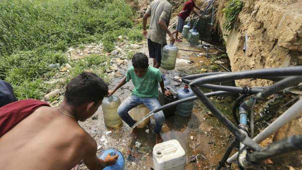 <p>Venezuela: Menschen sammeln Trinkwasser aus defekten Leitungen in der Nähe einer Barackensiedlung.</p>