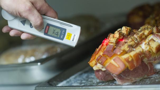 <p>Ein Lebensmittelkontrolleur überprüft die Temperatur einer Fleischware.</p>