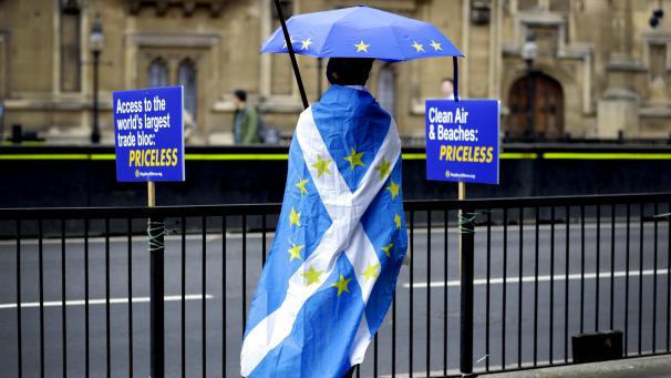 <p>Ein Anti-Brexit-Protestierender steht gegenüber dem Parlament Großbritanniens. Er trägt eine schottische Flagge mit Sternen der EU-Fahne auf dem Rücken.</p>