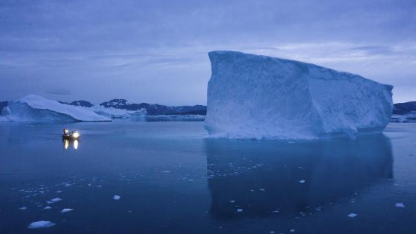 <p>Ein kleines Boot fährt an einem großen Eisberg in Ostgrönland vorbei. Mit der Erderwärmung dehnt sich das Meerwasser aus, die Eismassen schmelzen und der Meeresspiegel steigt. Den Einfluss von CO2 auf Meer und Eis beleuchtet ein neuer Report.</p>