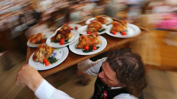 <p>Ein Kellner trägt auf dem Oktoberfest Hendl (Hähnchen) auf einem Tablett durch das Bierzelt: Für viele ist die Kultveranstaltung eine Gaudi, sie ist aber auch ein bedeutender Wirtschaftsfaktor.</p>