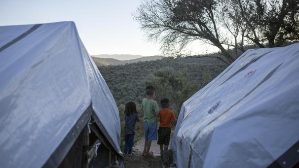 <p>Drei Kinder stehen zwischen Zelten in einem provisorischen Lager neben dem Flüchtlingslager von Moria.</p>