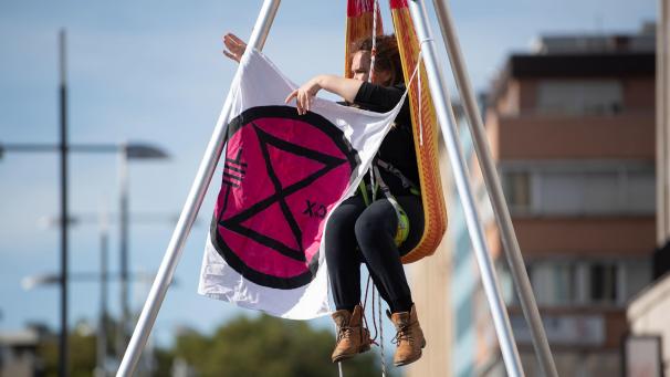 <p>Eine Aktivistin mit einer Flagge mit dem Logo der Bewegung „Extinction Rebellion“.</p>