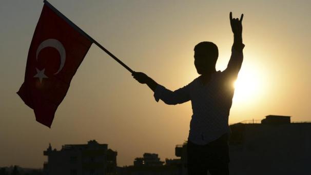 <p>Ein Mann schwenkt eine türkische Nationalflagge und feiert die Übernahme einer syrischen Provinz durch das türkische Militär.</p>
