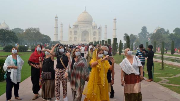 <p>Touristen besichtigen das Taj Mahal, mit Atemschutzmaske.</p>