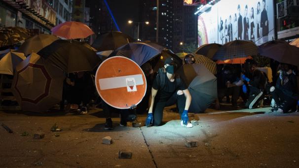 <p>Demonstranten bilden hinter Regenschirmen gegen die Polizei eine Barrikade.</p>