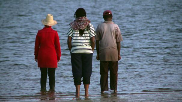 <p>Sarah Cameron Sunde (l.) steht mit zwei Menschen im Indischen Ozean, um auf den klimabedingt steigenden Meeresspiegel hinzuweisen.</p>