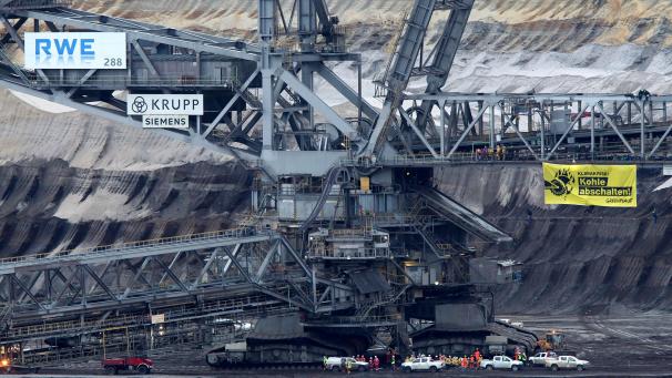<p>An einem Braunkohle-Bagger hängt ein Plakat mit der Aufschrift „Kohle abschalten! Greenpeace“.</p>
