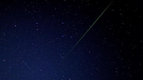<p>Hier ist zu sehen, wie eine Sternschnuppe am Nachthimmel einen hellen Lichtschweif hinter sich her zieht.</p>