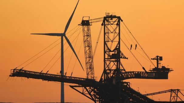 <p>Eine Windenergieanlage ist am frühen Morgen hinter einem Absetzer für Abraum im Braunkohletagebau Jänschwalde der Lausitzer Energie Bergbau AG (LEAG) zu sehen.</p>