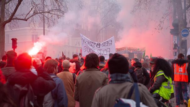 <p>Demonstranten halten während eines Protestes gegen die Rentenreform in Paris Plakate und zünden Leuchtfackeln.</p>