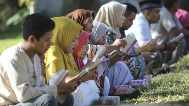 <p>Indonesien, Banda Aceh: Menschen lesen im heiligen Buch Koran bei einem Gebet an einem Massengrab für Opfer des Tsunami im Indischen Ozean während der Gedenkfeier zum 15. Jahrestag der Katastrophe.</p>