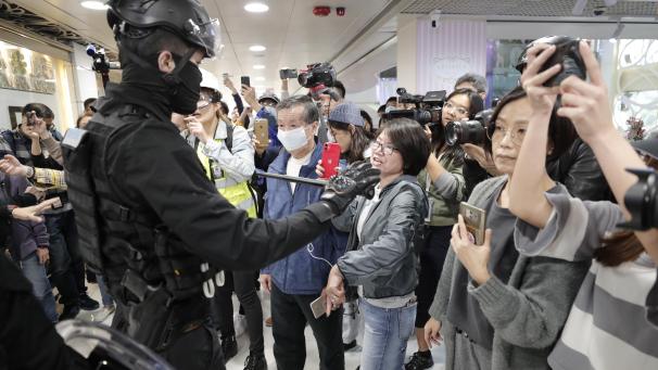 <p>Ein Polizist versperrt Fotografierenden während einer Demonstration mit einem Schlagstock den Weg.</p>