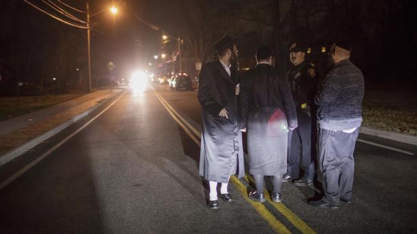 <p>Orthodoxe Juden sprechen nach einem Messerangriff mit einem Polizeibeamten (2.v.r) in der Forshay Road.</p>