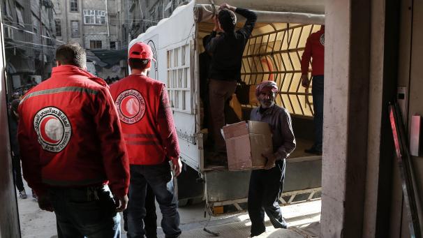 <p>Syrien, Duma: Freiwillige des Roten Halbmondes entladen einen UN-Hilfskonvoi.</p>