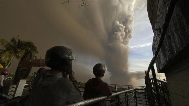 <p>Menschen beobachten auf einer Brücke in der philippinischen Provinz Cavite, südlich der Hauptstadt, riesige Rauchwolken, die während eines Ausbruchs von Vulkan „Taal“ in die Luft steigen.</p>