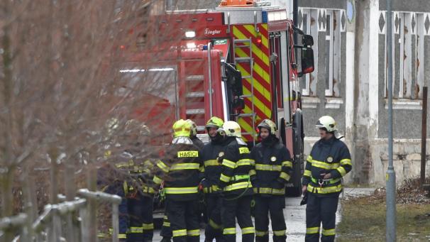 <p>Feuerwehrleute stehen während der Löscharbeiten an einem Einsatzwagen vor einem Pflegeheim für Behinderte.</p>