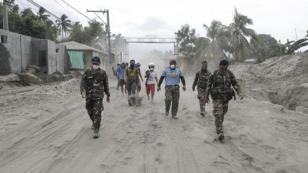<p>Philippinische Polizisten und Soldaten gehen auf einer mit Vulkanasche bedeckten Straße. Auf den Philippinen haben die Behörden die Menschen davor gewarnt, in ihre Häuser in der Nähe des Vulkans Taal zurückzukehren.</p>