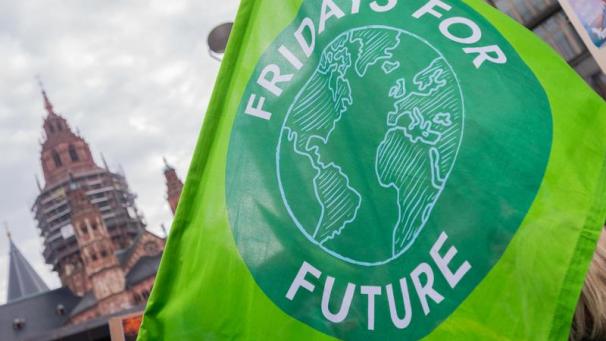 <p>Ein Teilnehmer steht mit einer Flagge mit dem Aufdruck „Fridays For Future“ bei einer Demonstration.</p>