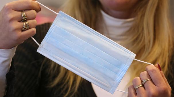 <p>Eine Apothekerin hält ein Atemschutzmaske in der Hand.</p>