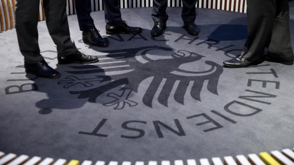 <p>Männer stehen auf einem Teppich mit dem Logo des Geheimdienstes während der Eröffnung des Besucherzentrums des Bundesnachrichtendienstes (BND).</p>