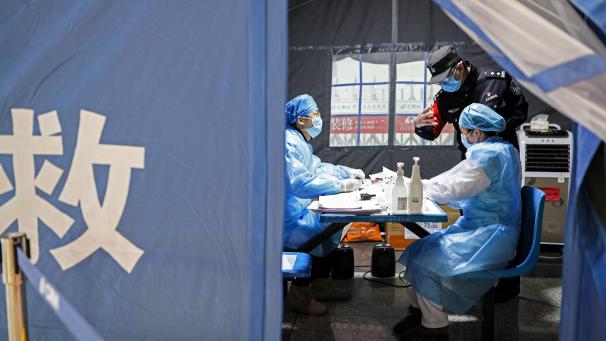 <p>Ein chinesischer Polizist spricht mit medizinischem Personal in einem Zelt am Guiyang Nordbahnhof. Um die Ausbreitung des Coronavirus zu verhindern und zu kontrollieren, haben Polizisten der Polizeistation des Bahnhofs dabei geholfen, die Temperaturen von Passagieren zu messen.</p>