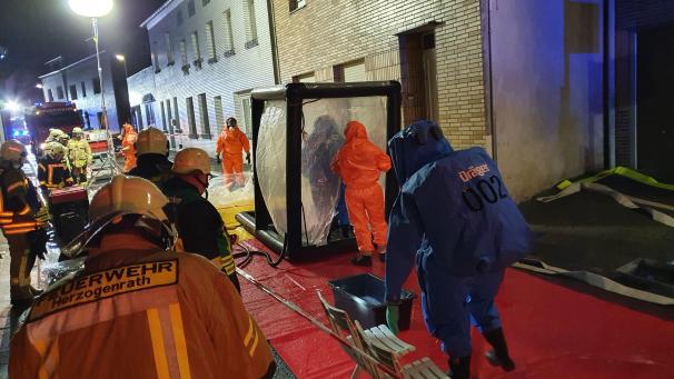 <p>Einsatzkräfte, teils in Schutzanzügen, stehen vor einem Wohnhaus in Alsdorf. Ein Rauchmelder hatte dort am Samstagabend Alarm geschlagen. In der Wohnung entdeckte die Feuerwehr eine „auffällige Anzahl von verschiedenen Chemikalien“.</p>