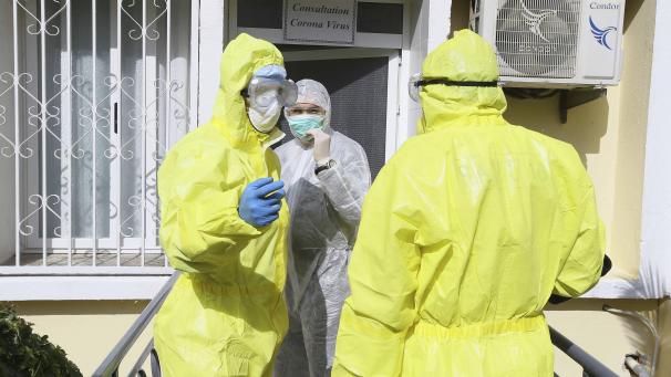 <p>Algerien, Algier: Mediziner stehen in Schutzanzügen und mit Mundschutz am Eingang einer Klinik.</p>